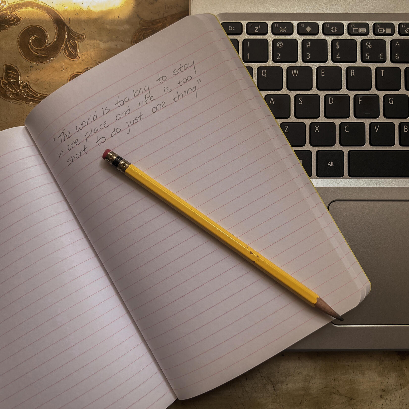 Notebook on Computer Notebook laying on a laptop, with a handwritten quote.